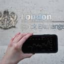 A view of the Stocks app on an iPhone against the London Stock Exchange sign in the City of London, as the FTSE 100 Index crashed on opening by more than 230 points to 7,104.94 as inflation fears continue to rock global markets
