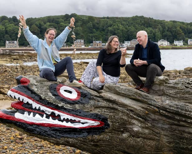 Three people sitting on the crocodile rock at Largs