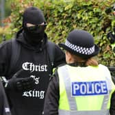 Two police officers speaking to a man wearing a balaclava