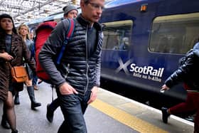 Passengers walking along a platform next to a blue ScotRail train