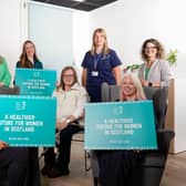 A group of women hold signs about inequalities in women's health to raise awareness for a charity's new women's health action plan