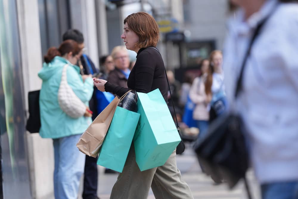 A woman walking on a high street carrying several shopping bags