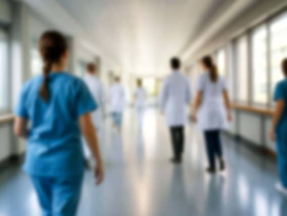 Blurred figures of doctors and nurses walking in a hospital corridor