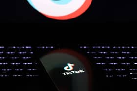 Phone with TikTok logo on the screen placed on the keyboard of a laptop in the dark