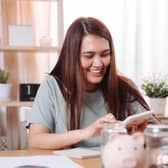 Young happy woman sitting at a desk on phone sorting out her finances