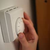 A person adjusting a central heating thermostat