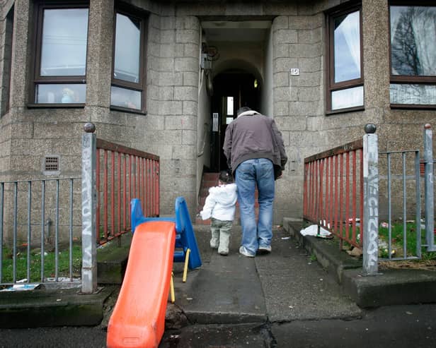 An adult and child enter a rundown block of flats