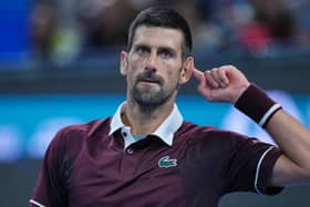 Novak Djokovic holds his finger to his ear