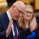 John Swinney speaking in Holyrood, with both hands raised