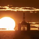 An oil rig with a sunset in the background