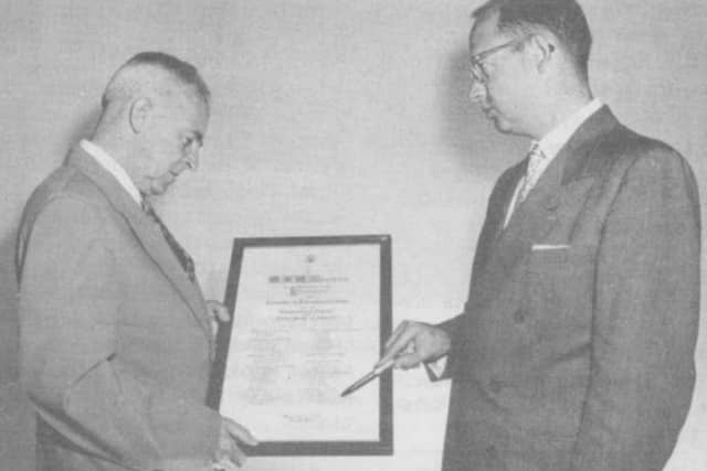 George Browne, on the left, receiving a certificate of recognition for his life-saving radio work from a member of the US Embassy.
