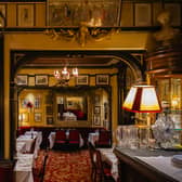 Looking through an archway towards formal dining tables, with artworks on all the yellow-painted walls