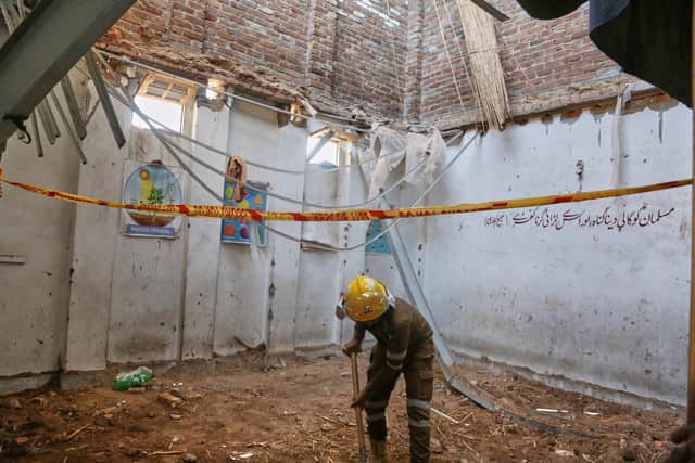 A rescue worker searches through the rubble at a school in Peshawar (Muhammad Zubair/AP)