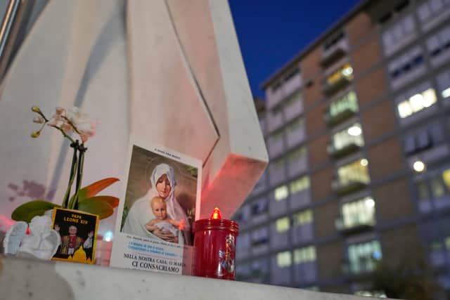 An image of Pope Leo rests at the base of a statue of late pope John Paul II outside the hospital where Leo had surgery (Gregorio Borgia/AP)