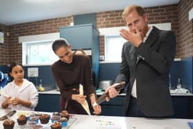 Harry licks icing from his hand as he and the Meghan decorate birthday cupcakes during a visit to Epic Partners in Nottingham