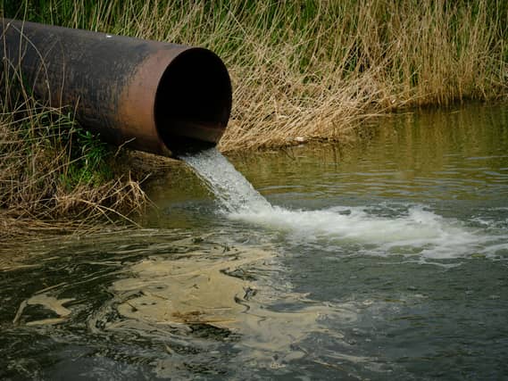 Draining sewage from pipe into river, pollution rivers and ecology