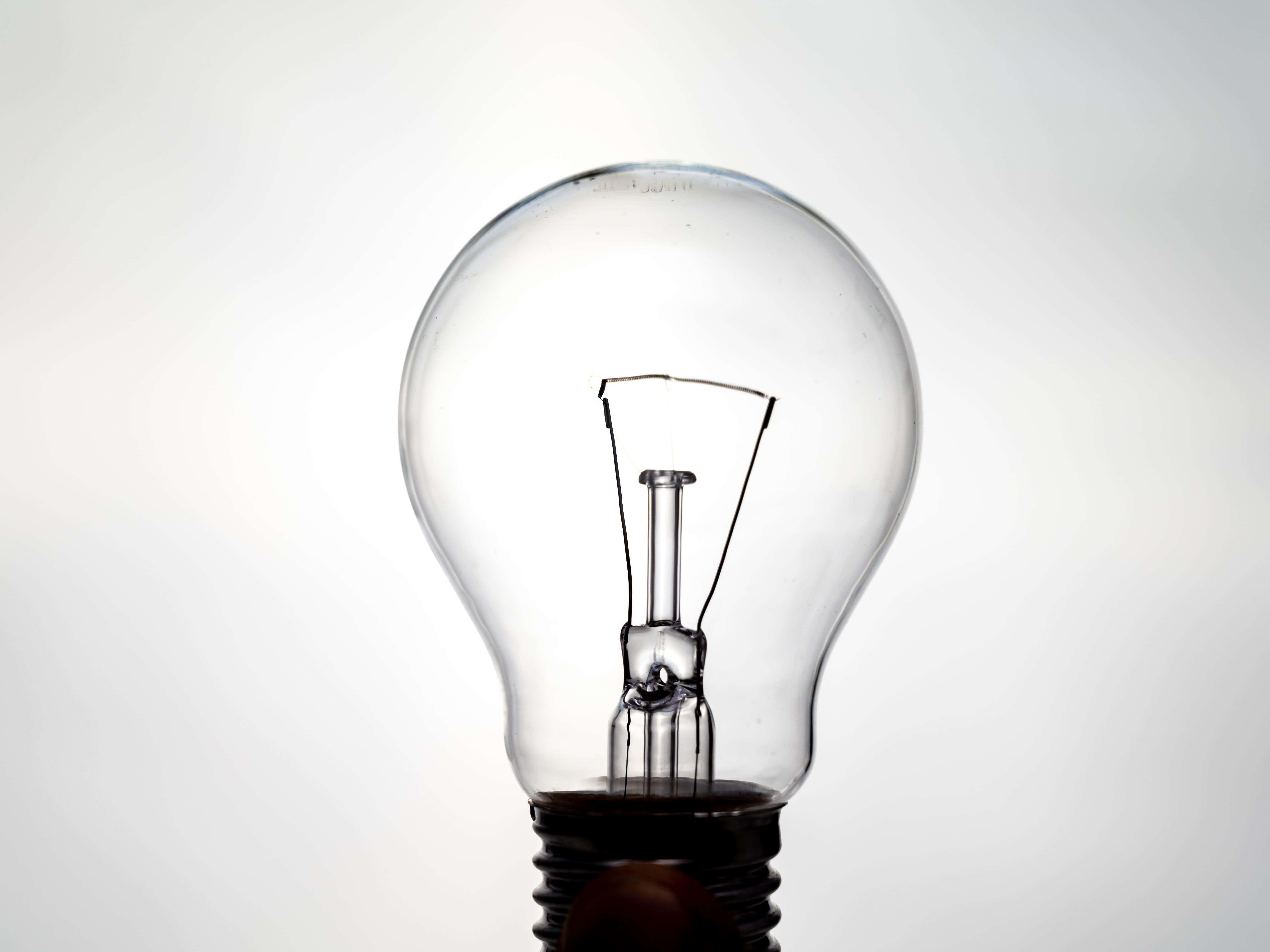 Incandescent light bulb, photographed against the light, which appears to be on. Electricity and renewable energy sources.