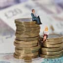 Models of a man and woman stand on a pile of coins and bank notes