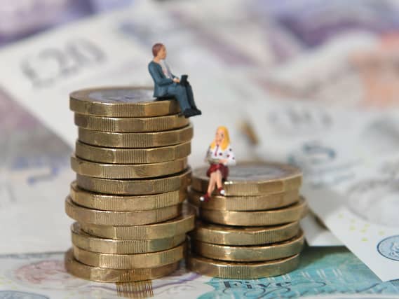 Models of a man and woman stand on a pile of coins and bank notes