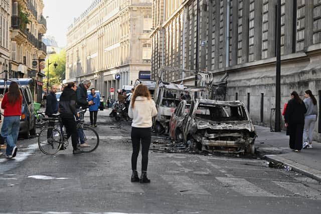 People look at charred cars in the French capital (Emma Da Silva/AP)