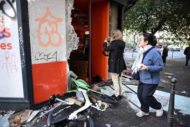 A woman takes a photo of a looted shop in Paris (Emma Da Silva/AP)