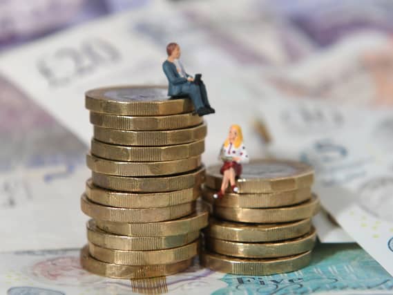 Models of a man and woman standing on a pile of coins and bank notes