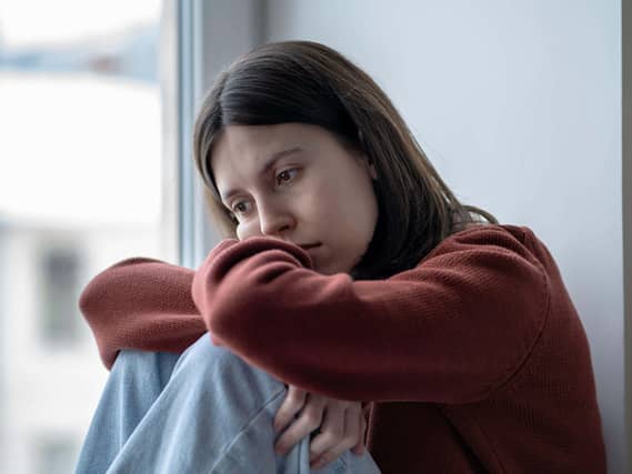 Anxious, unhappy teen resting her head on her arms and knees