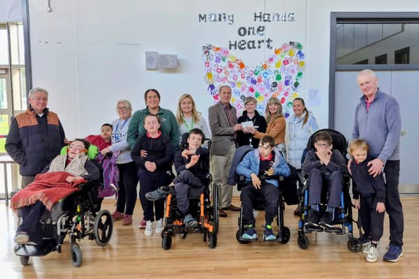 Gerry Kelly (MC), pupils and staff at Kolbe Special School, and Philip Greene (Stradbally Union of Parishes Treasurer) present the €1,500 cheque to Yvonne Hennessey (VP of Kolbe Special School), Annette Jones (Fashion Show Co-ordinator), and Della Dineen (MC) 