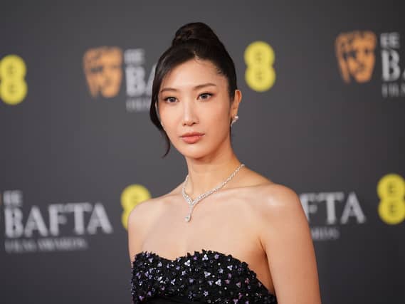 Ejae posing for photos at the Baftas in a black gown