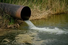 Draining sewage from pipe into river, pollution rivers and ecology