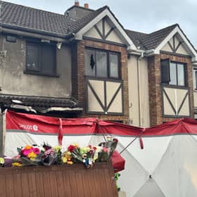 External view of a house showing signs of fire damage, with a forensic tent erected outside