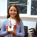 Ava Mitchell smiling, holding up a poppy