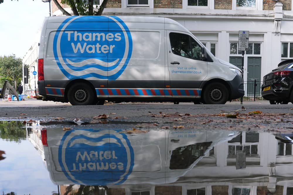 Thames Water van parked on a street, opposite a large puddle of water