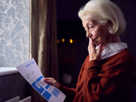 Senior woman standing in her home looking at an energy bill letter
