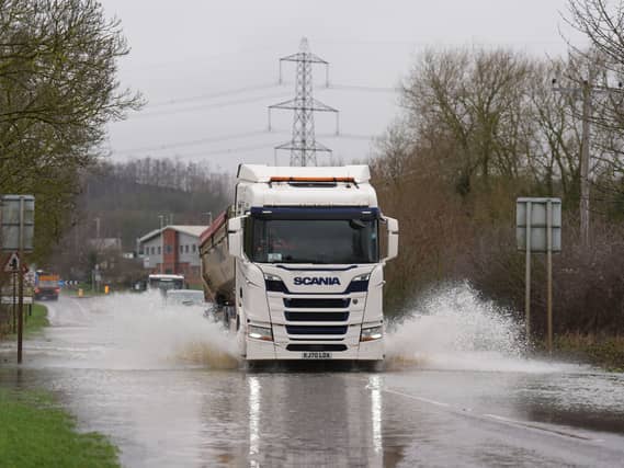 A lorry driving along a flooded road, causing heavy spray
