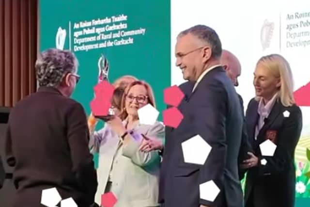 Mary White raises the trophy watched by chair Robbie Quinn, as Abbeyleix Tidy Town wins 2026 Ireland's Tidiest Small Town Award.