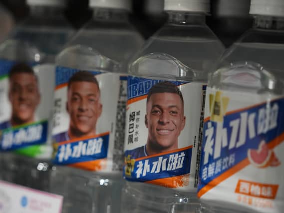 Bottles of an electrolyte drink by Dongpeng Beverage Group featuring images of French football star Kylian Mbappe displayed for sale at a supermarket in Beijing
