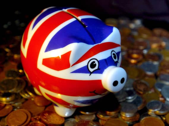 A Union flag piggy bank standing on a pile of coins