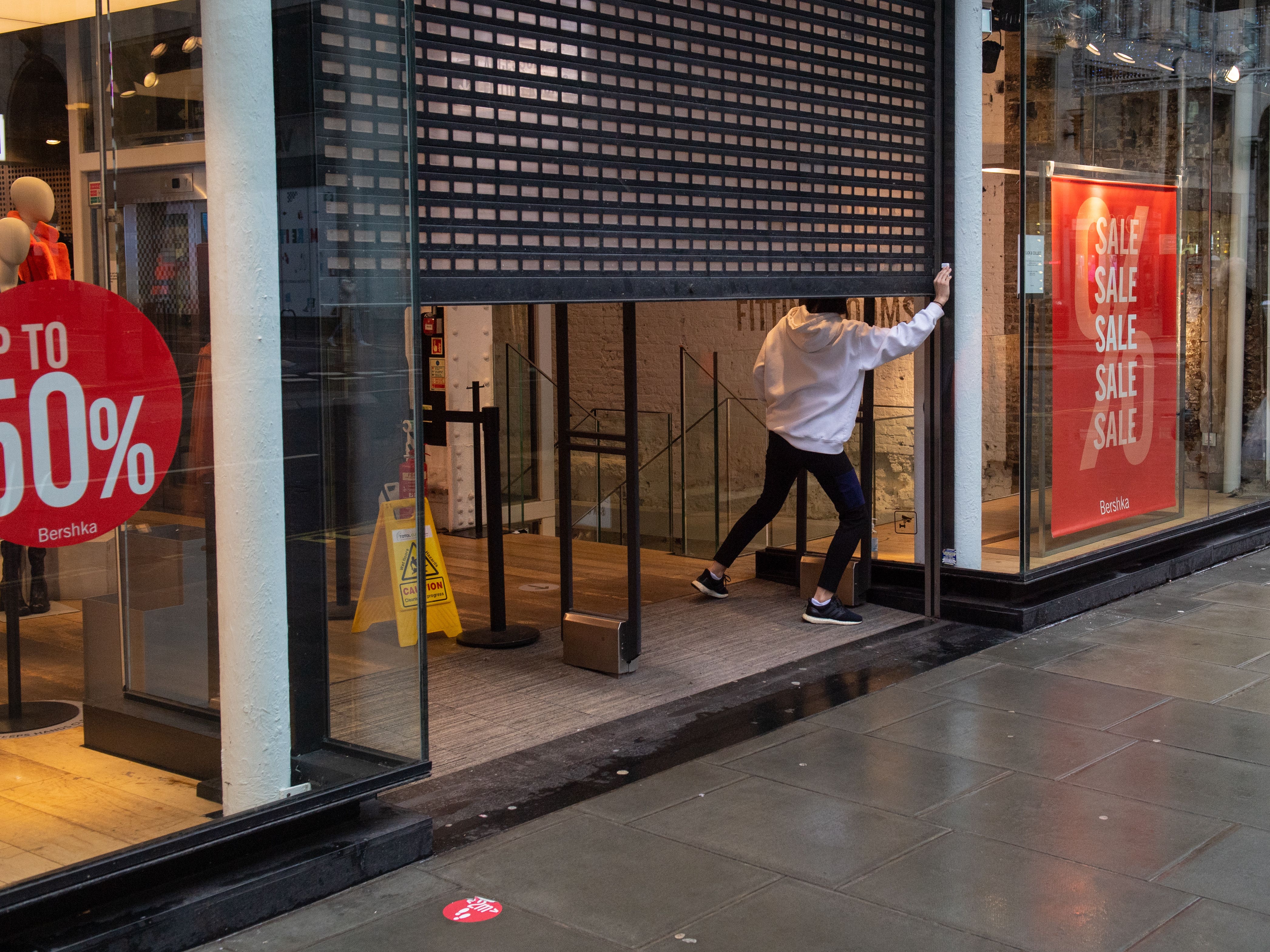 A shop worker closes the shutters