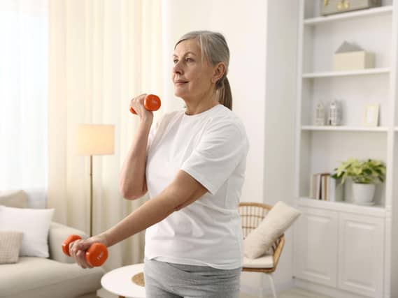 Senior woman exercising with dumbbells at home.
