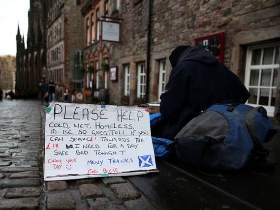 A homeless person with a sign sitting in an Edinburgh street