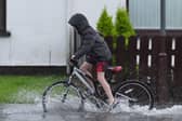 A boy riding a bike down a flooded street