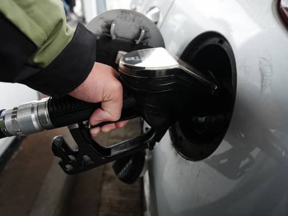 A person fills a car with petrol at a petrol pump