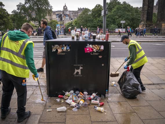 Refuse workers clean up an overflowing bin