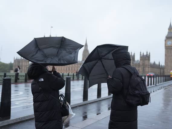 People struggle with umbrellas on Westminster Bridge in London on October 24 2026, due to the impact of Storm Boelo