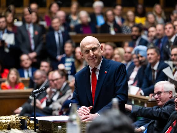 A photograph of John Healey stood at the dispatch box of the House of Commons with MPs behind him
