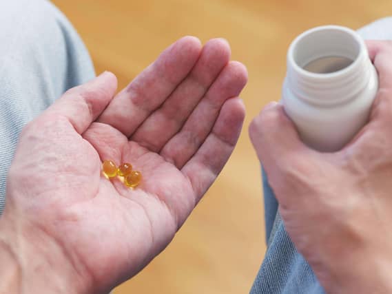 A man holding vitamin D3 capsules from a plastic bottle in his palm