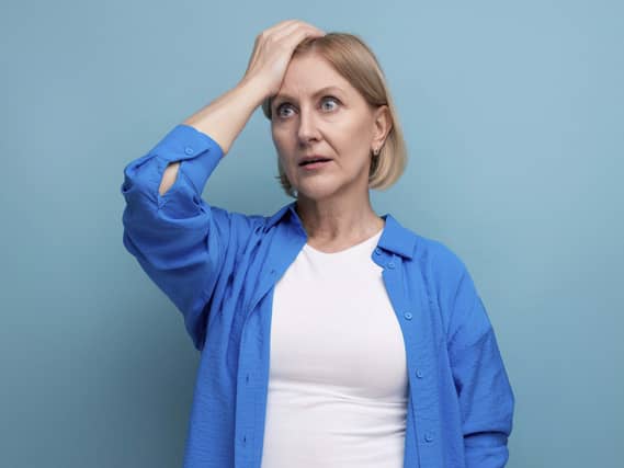 Menopausal women experiencing brain fog putting one hand on her forehead looking confused