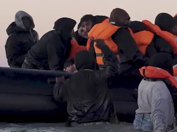 A person holding what appears to be a knife (in water on left) as people thought to be migrants attempt to board a small boat off the coast of Hardelot, France, on Friday
