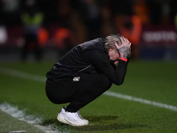Peterborough manager Robbie Savage holds his head in his hands